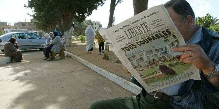 An Algerian reads the 26 May 2003 "Liberte" newspaper titled " All guilty" 26 May 2003, at the entrance of El Alia cemetery in Algiers. The Algerian government scrambled Monday to dispel criticiem it has dragged its heels in helping victims of last week's deadly quake, as Islamic radicals took advantage of the widespread anger towards the authorities and stepped in to fill the void. AFP PHOTO/PHILIPPE DESMAZES (Photo by PHILIPPE DESMAZES / AFP)