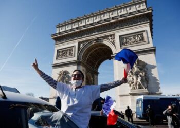 Protesters wave French flags on the Champs-Elysees avenue as cars parade during their "Convoi de la liberte" (The Freedom Convoy), a vehicular convoy to protest coronavirus disease (COVID-19) vaccine and restrictions in Paris, France, February 12, 2022. REUTERS/Benoit Tessier