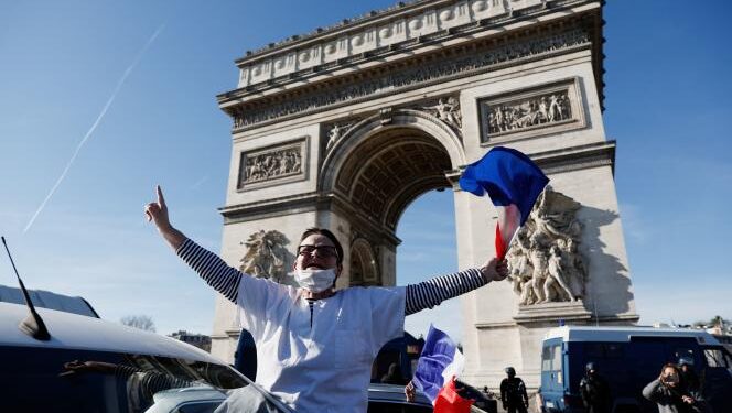 Protesters wave French flags on the Champs-Elysees avenue as cars parade during their "Convoi de la liberte" (The Freedom Convoy), a vehicular convoy to protest coronavirus disease (COVID-19) vaccine and restrictions in Paris, France, February 12, 2022. REUTERS/Benoit Tessier