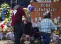 People pay their respects at a memorial outside Robb Elementary School to honor the victims killed in this week's school shooting in Uvalde, Texas Saturday, May 28, 2022. (AP Photo/Dario Lopez-Mills)